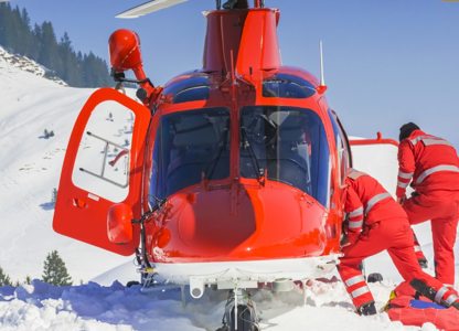 Rescue helicopter landed on a snowy mountainside with two emergency responders